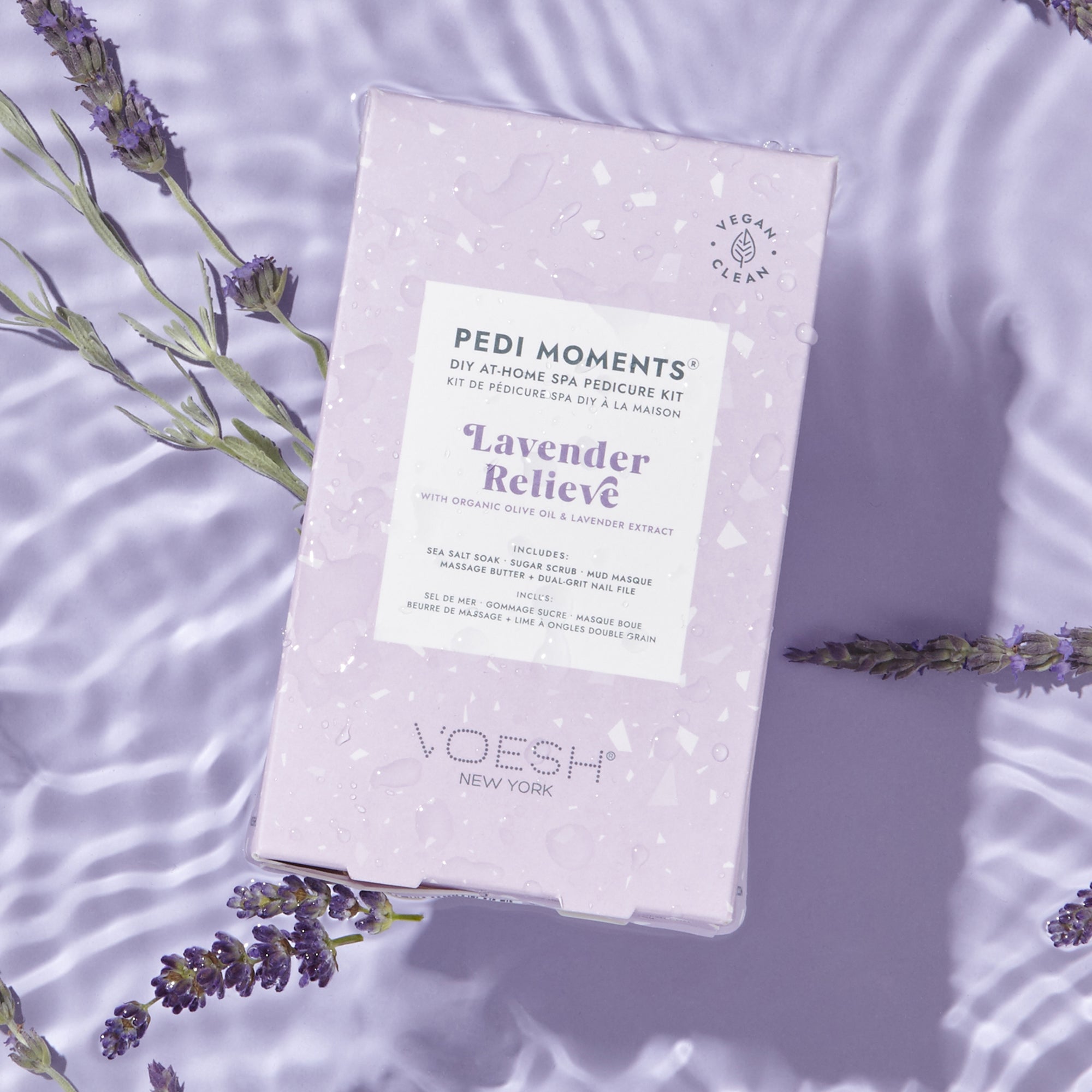 VOESH Pedi Moments Lavender Relieve pedicure kit on a purple background with lavender flowers.